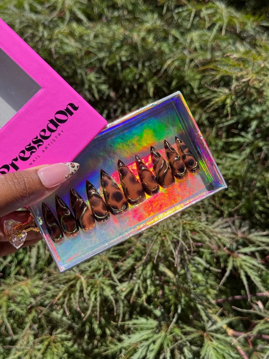 Medium stiletto press-on nails feature a brown cheetah print design with 3D gold accents.