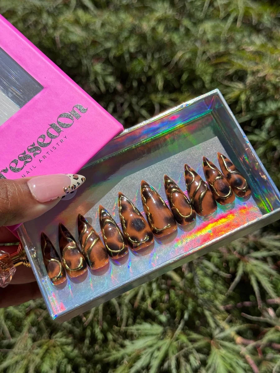 Medium stiletto press-on nails featuring a brown cheetah print with 3D gold accents. The set features a glossy finish.