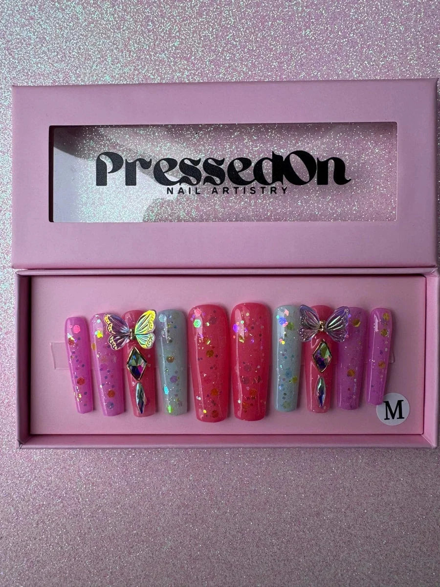 Long coffin press-on nails in pink, coral and light blue shades. These acrylic nails feature a glitter finish, rhinestone gems and 3D butterfly charms.