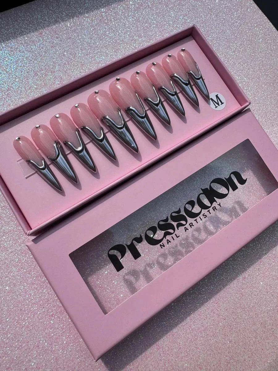 Long pink stiletto press-on nails feature chrome tips. Each nail has a reflective chrome design creating a modern, edgy aesthetic.