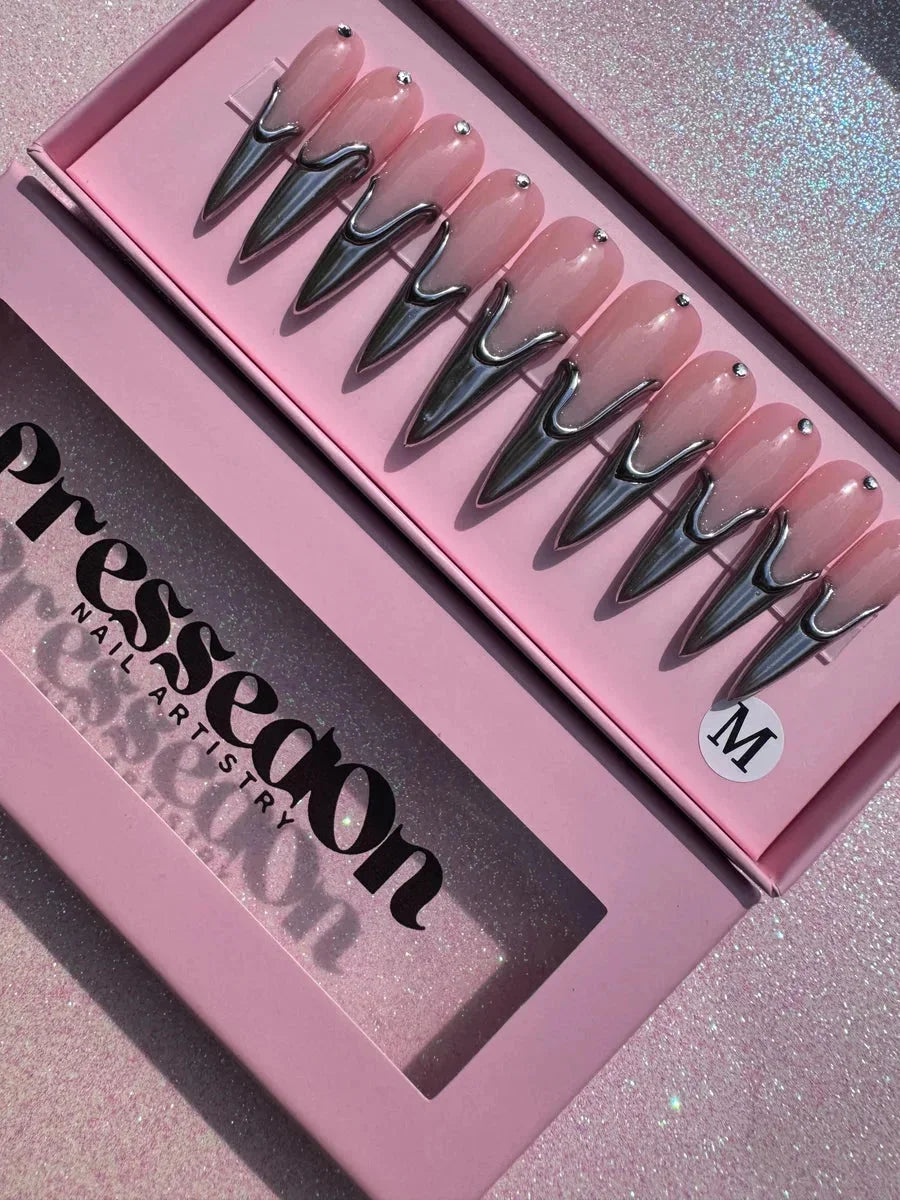 Long pink stiletto press-on nails with a shiny silver chrome accent at the base and a single rhinestone at the top of each nail.