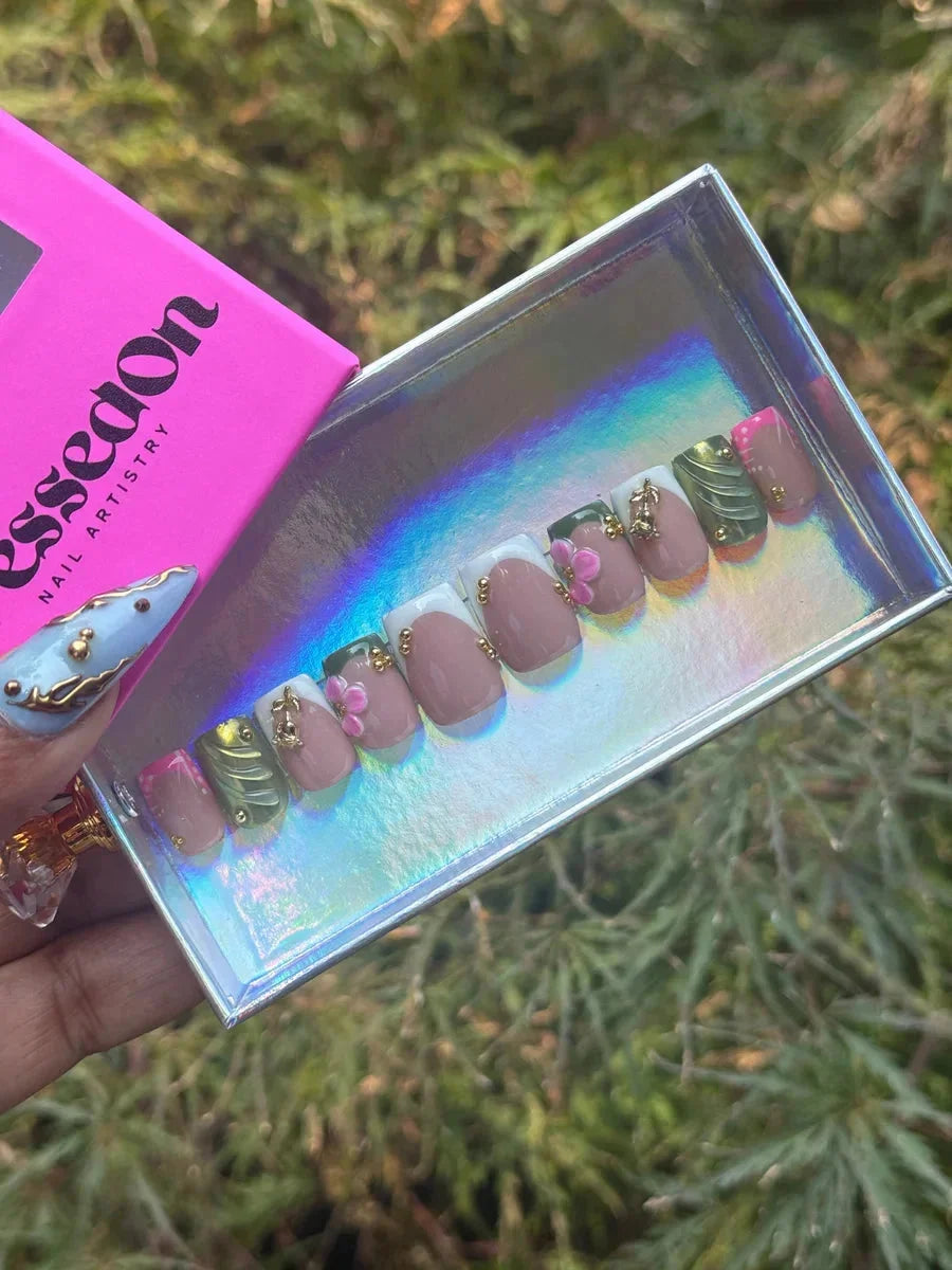 Super short square press-on nails feature a 3D floral design, French tips, pink, green, and neutral colors, and gold accents.