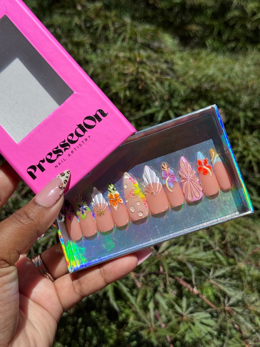 Peach-toned medium length press-on nails decorated with intricate 3D flower and butterfly designs, accented with rhinestones.