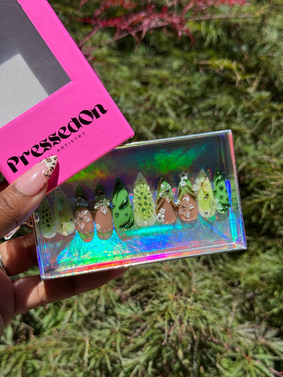Medium-length press-on nails with a 3D kiwi design, green leaves, and brown floral accents. The nails feature a mix of green, brown, and clear elements.