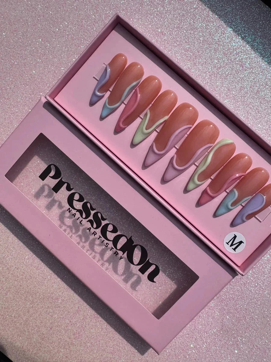 Long stiletto press-on nails feature a 3D swirl design with pastel lavender, mint, and pink accents.