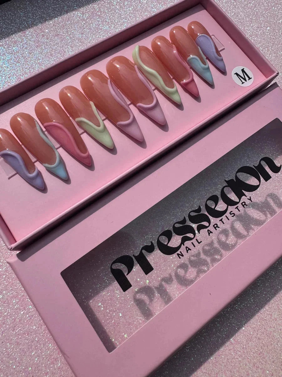 Long stiletto press-on nails feature a glossy finish and 3D pastel swirl designs in lavender, mint, pink, and blue. The nails have an elegant and artistic style.