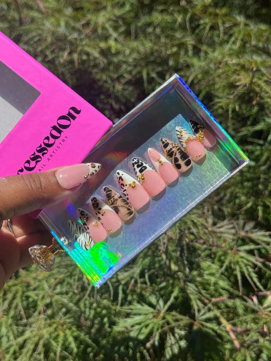 Short stiletto press-on nails feature animal prints like leopard and zebra, blush pink polish, and gold accents.