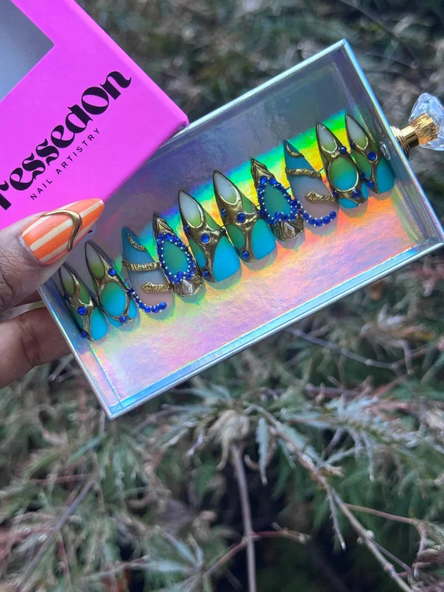 Aqua pointed press-on nails with blue gemstones, gold accents, and snake detailing. The set combines aqua, seafoam green, and gold for an eye-catching design.