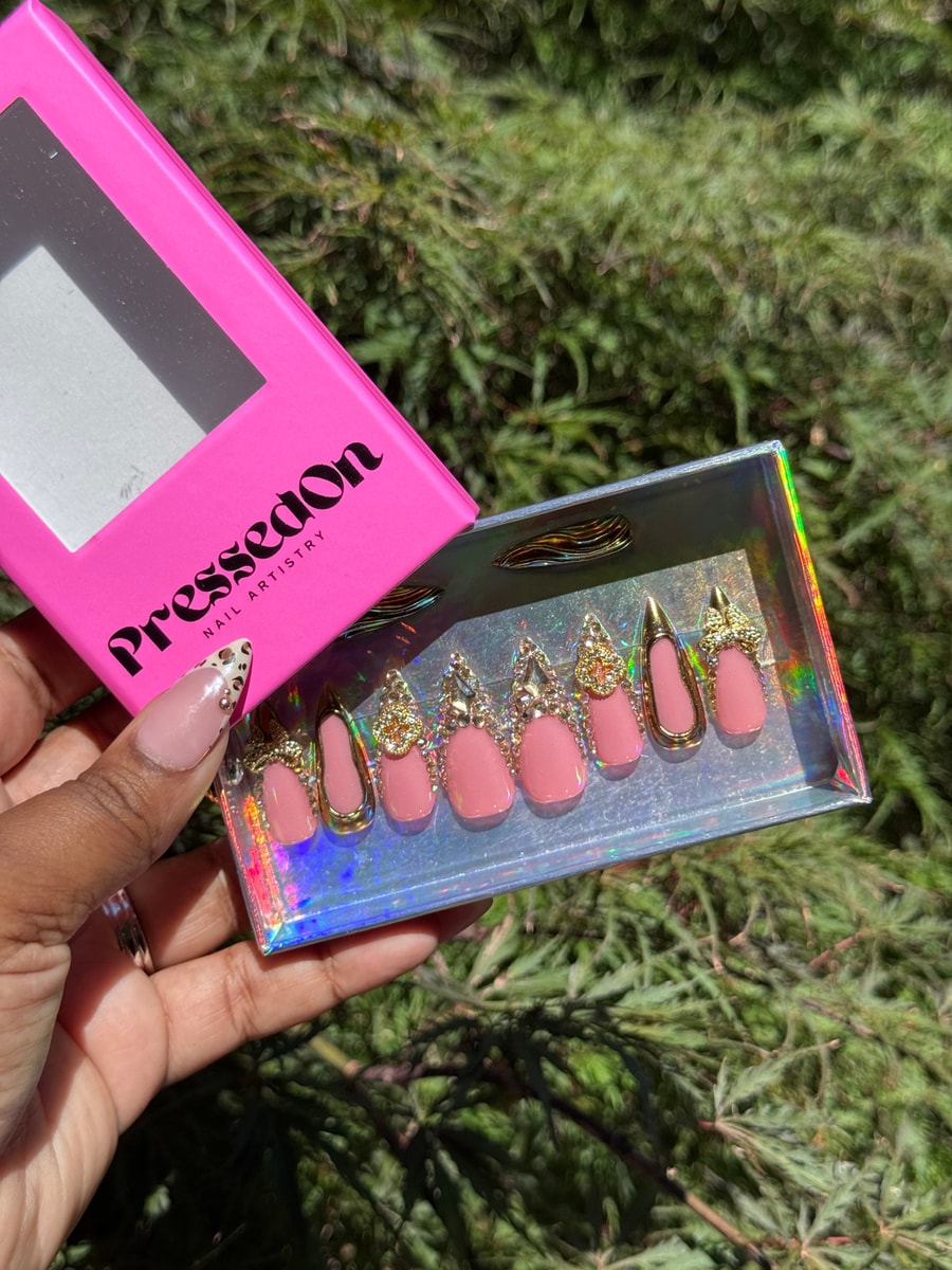 Pink press-on nails with gold and rhinestone embellishments. The set includes varied designs with crystal and gold accents.