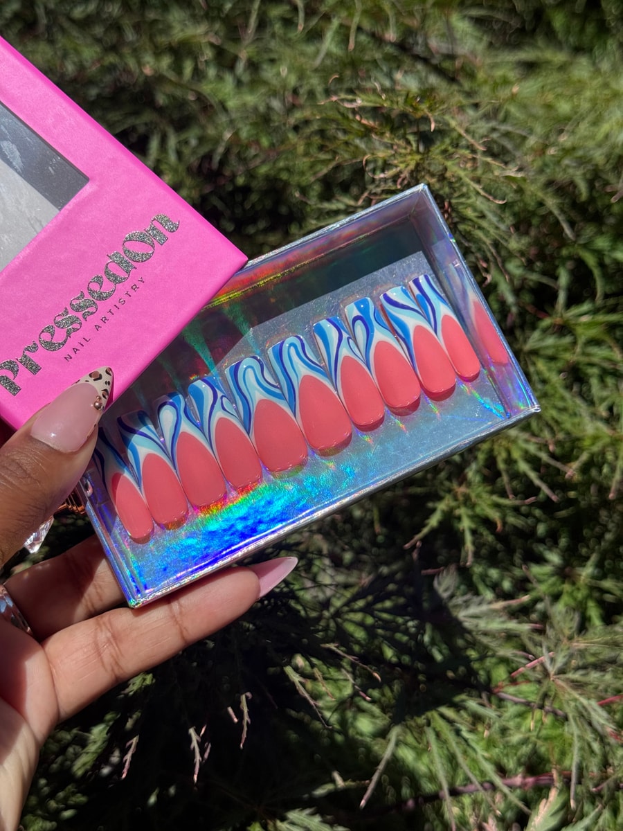 Coral medium-length press-on nails with blue and white wave accents. The set features a unique and eye-catching wavy design.