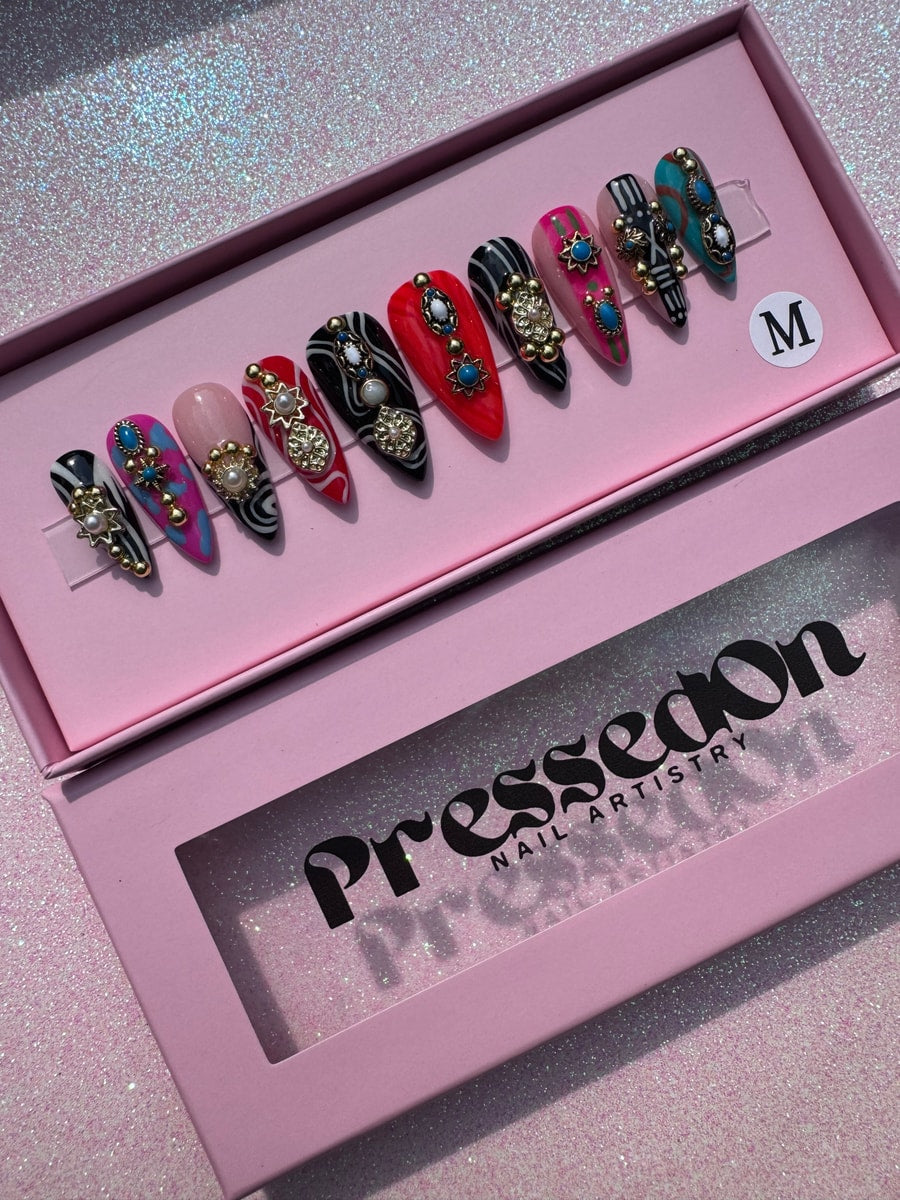 Set of short stiletto press-on nails featuring boho inspired junk style embellishments. Designs include zebra stripes, tie dye, red, and solid color nails.