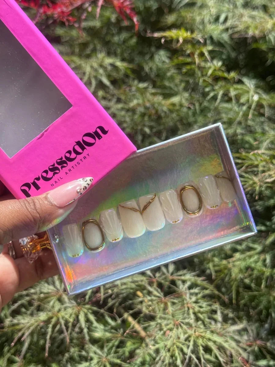 Ivory white super short press-on nails feature a 3D seashell design, gold accents, and gold oval details.