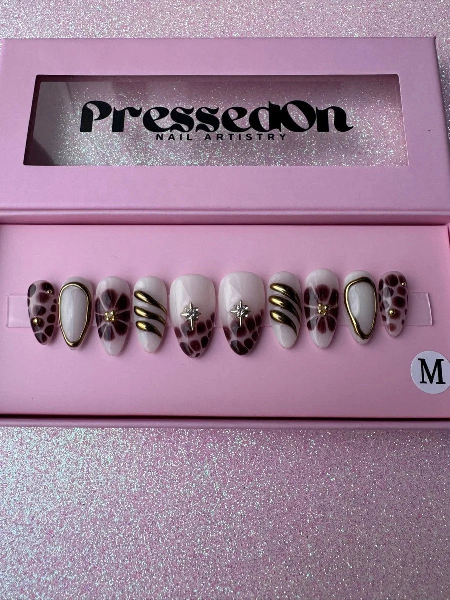Super short press-on nails with bronzed brown, white and gold designs. Features include floral patterns, geometric shapes, spots, a shimmering star, and gold accents.