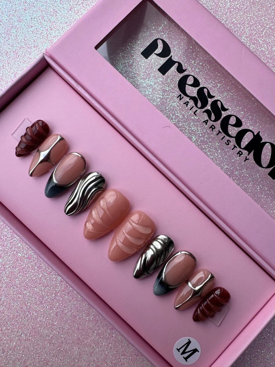 This set features short, almond-shaped press-on nails with chrome accents and a nude pink base.  A few nails have a full chrome effect and brown textured design.
