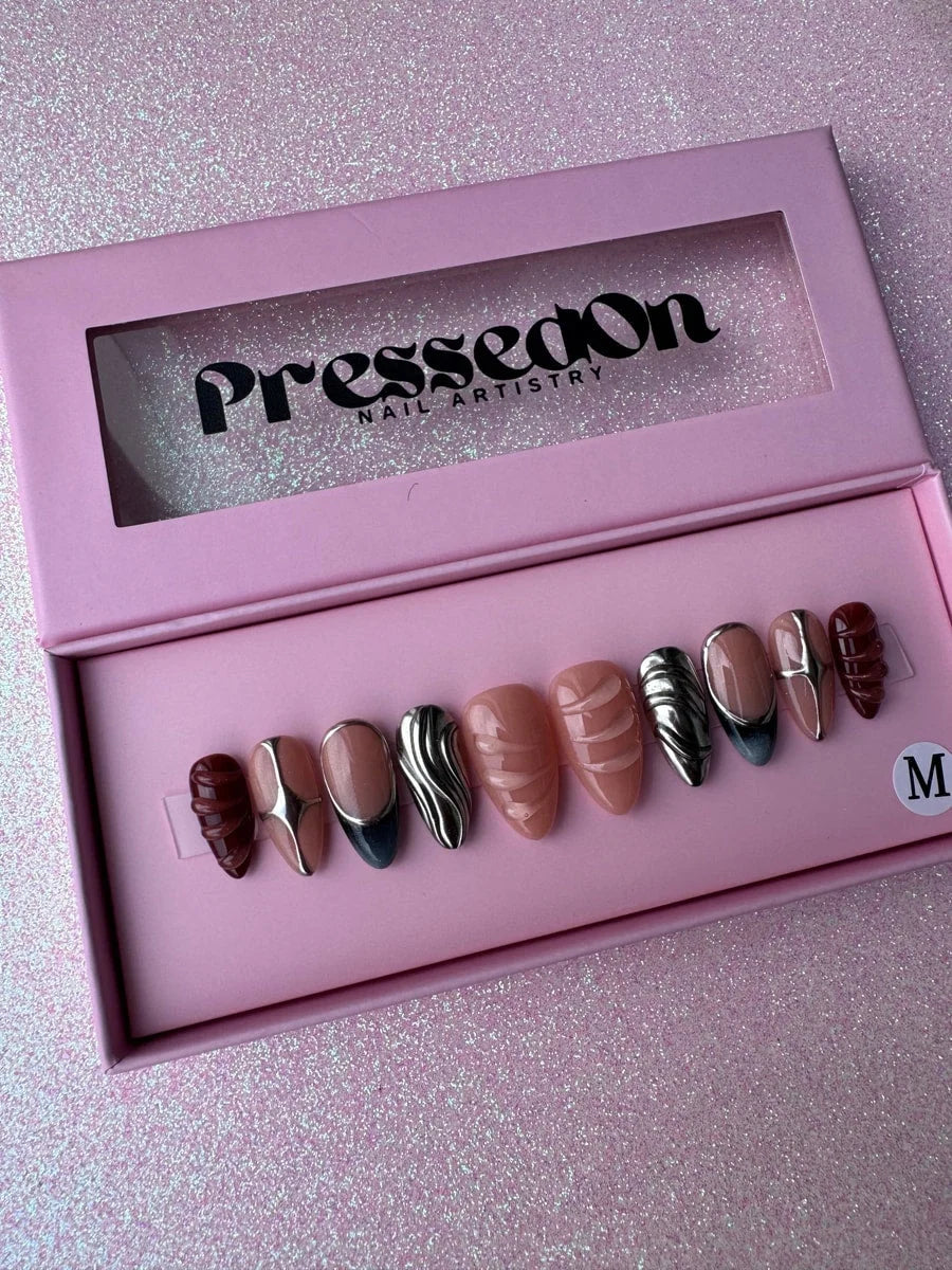 Set of super short press-on nails with chrome accents and unique designs, including nude, silver chrome, and deep red-brown sculpted nails.