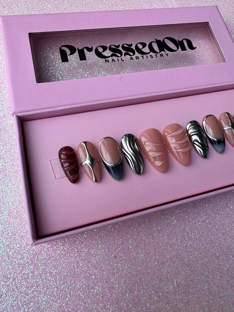 Super short press-on nails featuring chrome accents in nude, silver, and deep red-brown with sculpted details and unique designs.