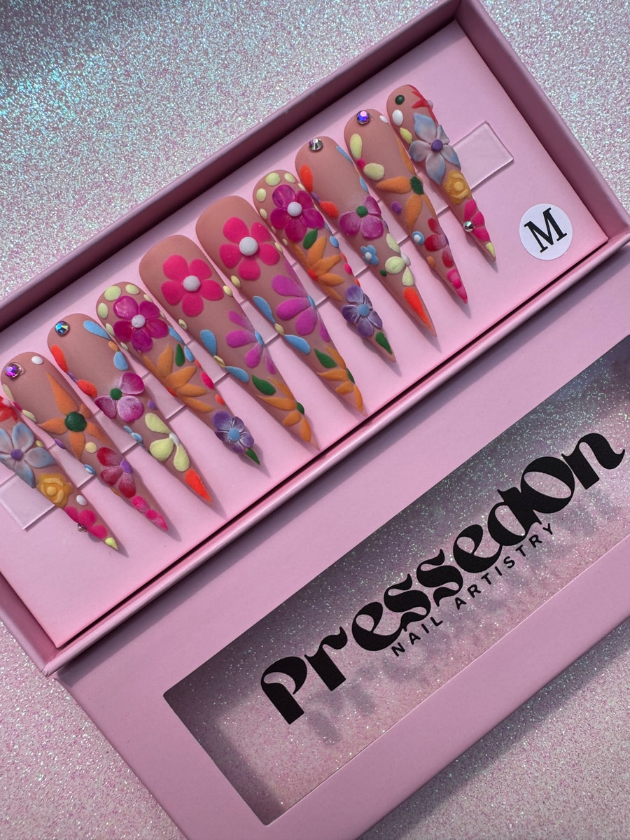 Xtra long stiletto press-on nails featuring a nude base with colorful, raised 3D floral decorations.