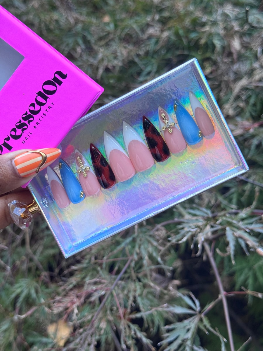 French twist press-on nails in medium length. The set includes classic white tips, tortoise shell tips, blue tips, nude pink and neutral base colors, and gold cross charms.