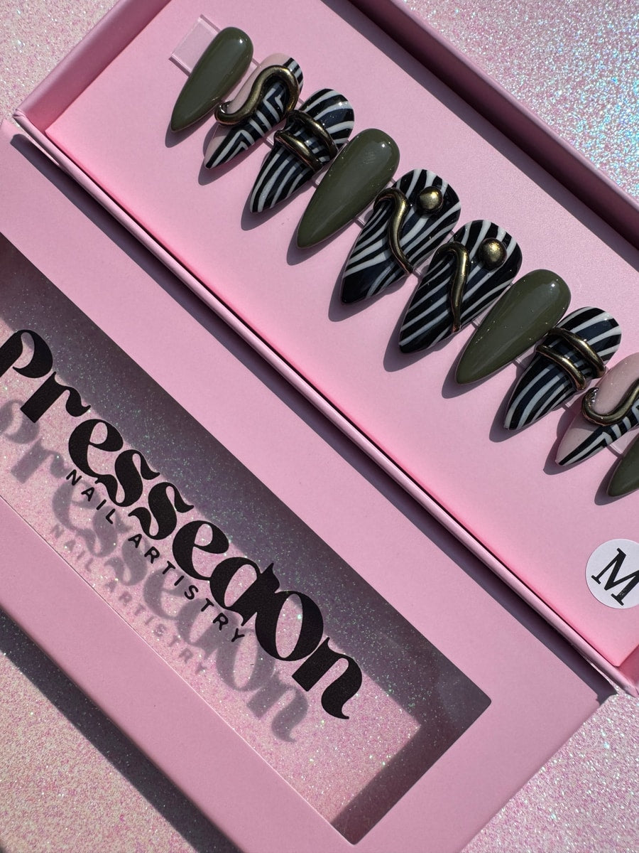 Geometric press-on nails in zebra stripe and solid olive green designs with gold accents. These are super short nails.