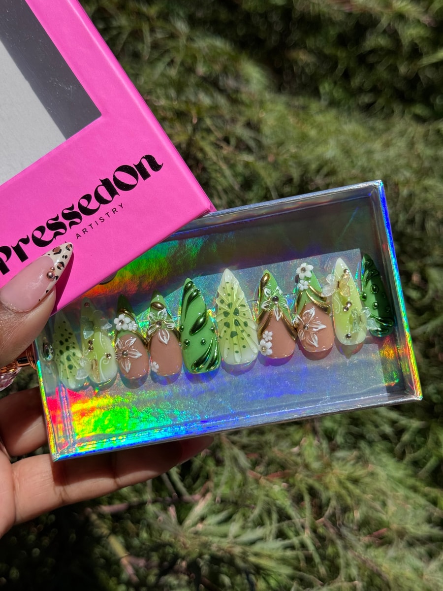 Medium length kiwi green and brown press-on nails featuring 3D flower and leaf designs. The nails have a mix of green shades, light brown accents and white flower charms.