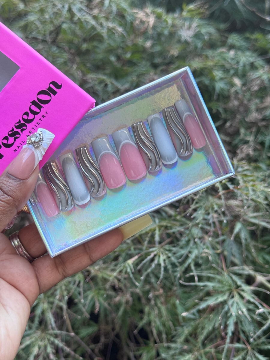This set of medium-length press-on nails features a grey and pink color scheme with a wavy silver accent design.