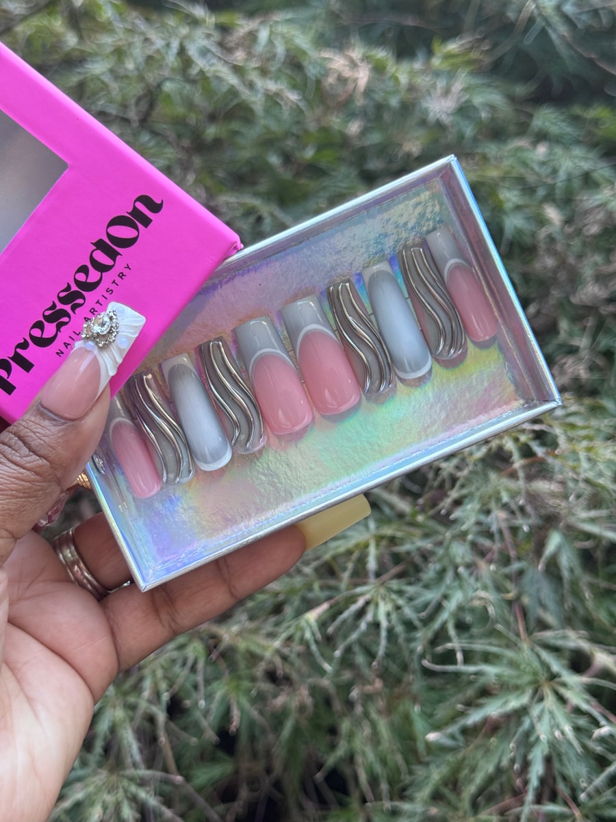 The image shows grey and pink medium-length press-on nails with a chrome wave design. Some nails have a French tip style with grey or pink polish.