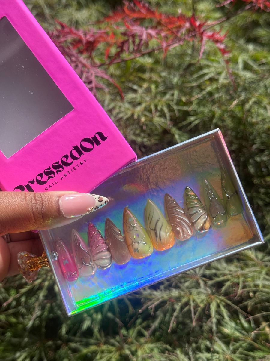 Set of medium length press-on nails featuring a butterfly wing design in translucent pink, brown, green and beige shades.