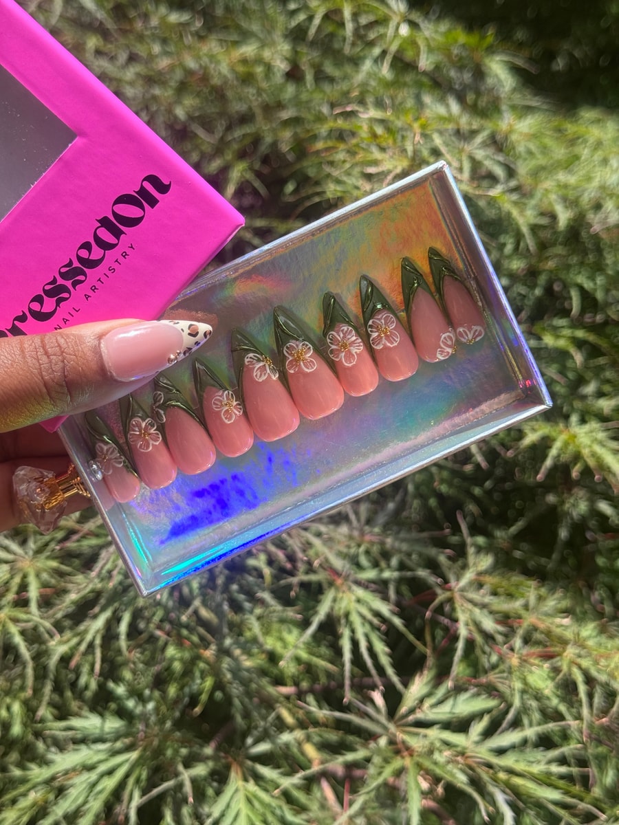 Medium press-on nails with a pink base and a delicate jasmine floral design. Each nail is decorated with white flowers accented by gold centers, complemented by green leaf details near the nail tips.