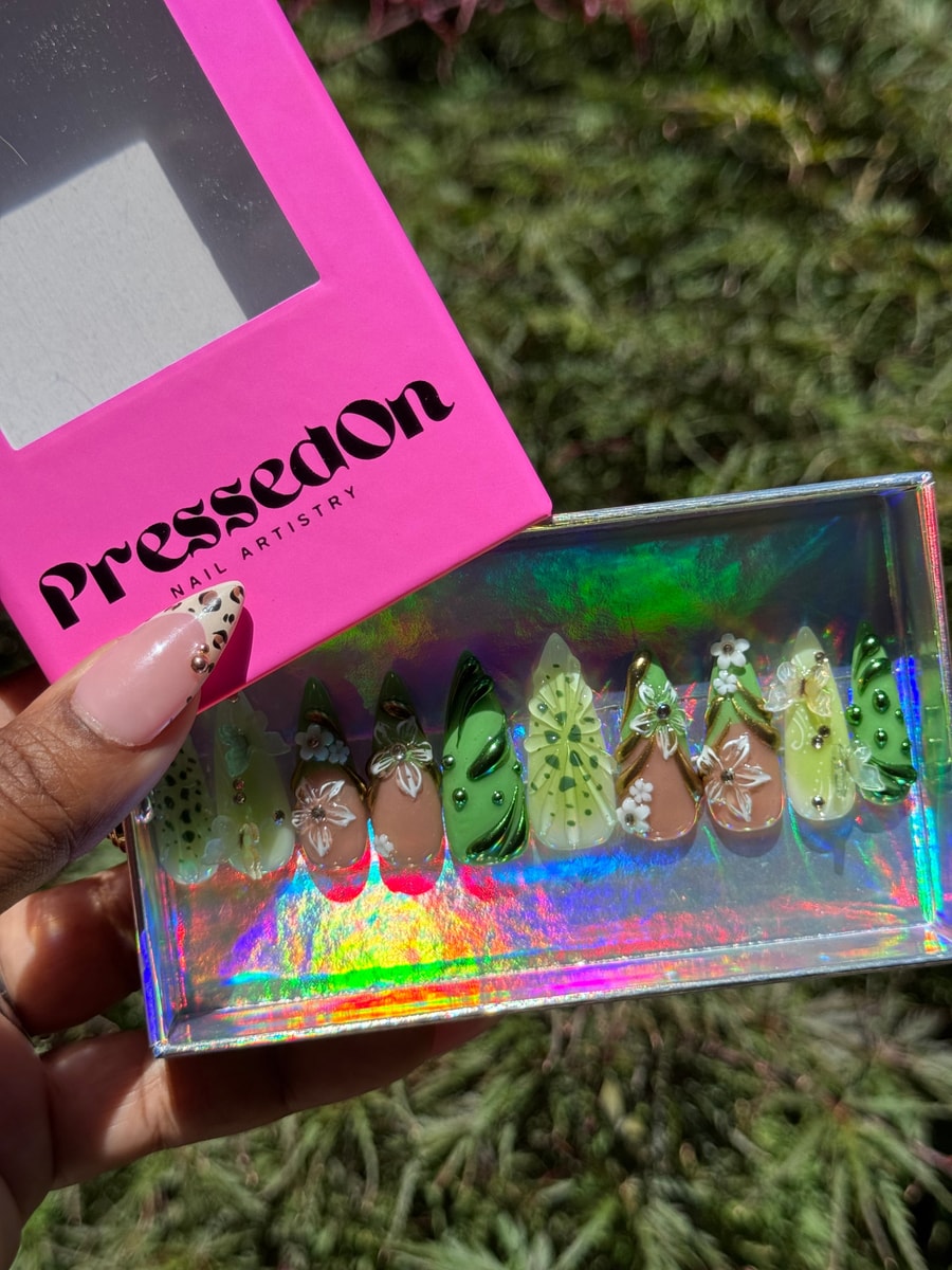 Medium-length press-on nails in shades of kiwi green with 3D floral accents. Designs vary, including floral patterns, rhinestones, and different green tones.