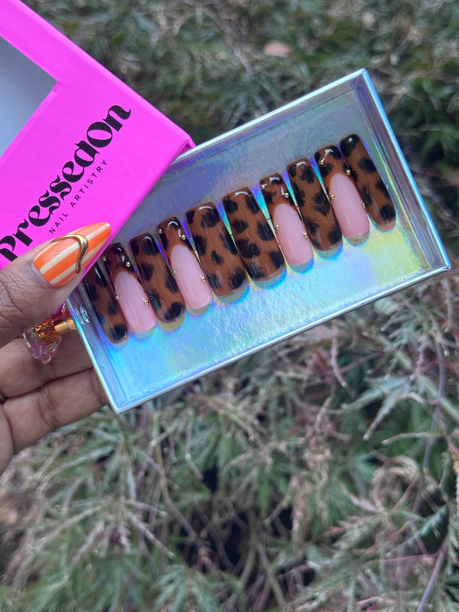 These are medium length press-on nails with a leopard print design over a light pink base, accented with small gold studs.