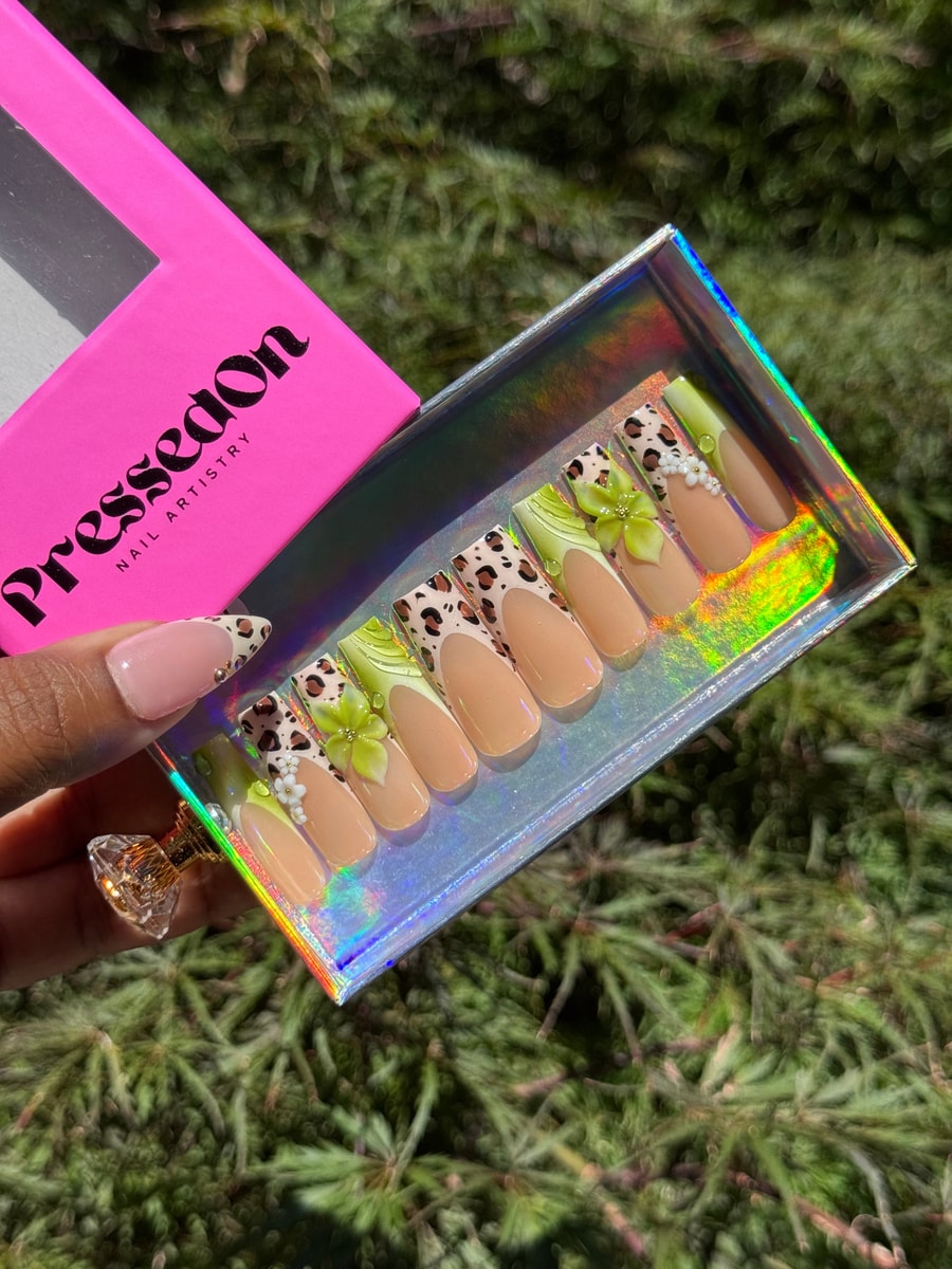 Set of medium-length press-on nails. They feature a cheetah print design, lime green accents, and small white and gold flower decorations.