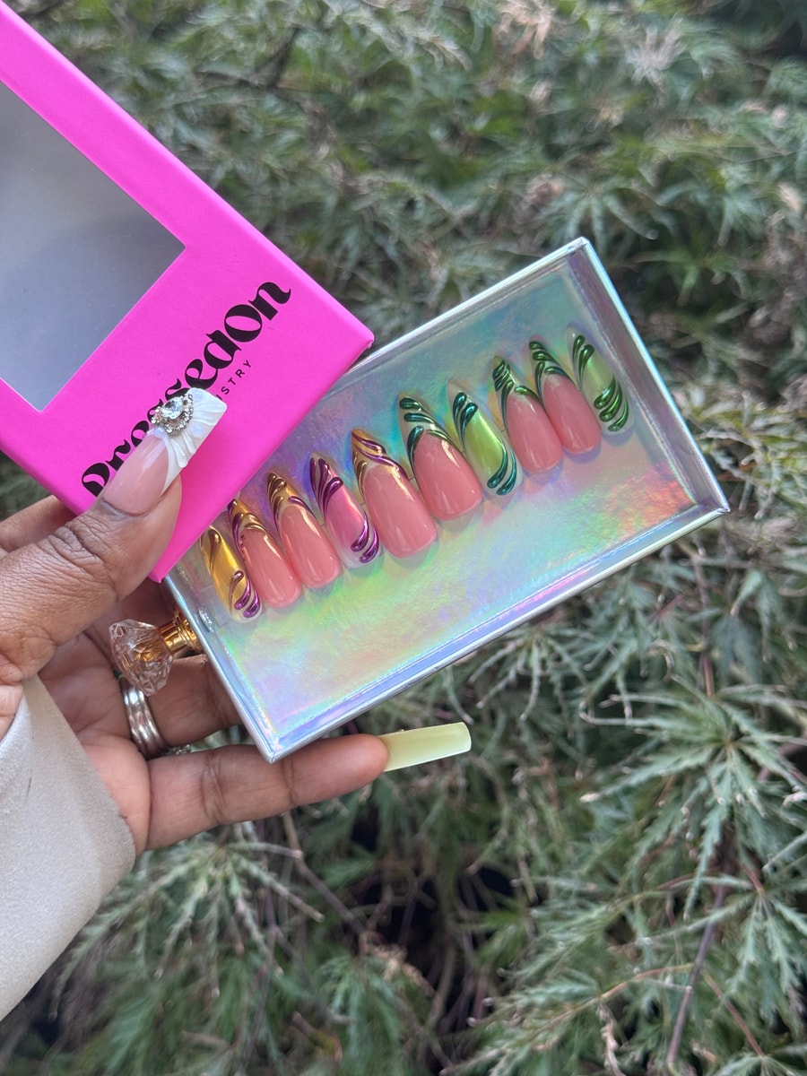 These are medium length pink press-on nails with 3D swirl accents in gold, green, and purple.