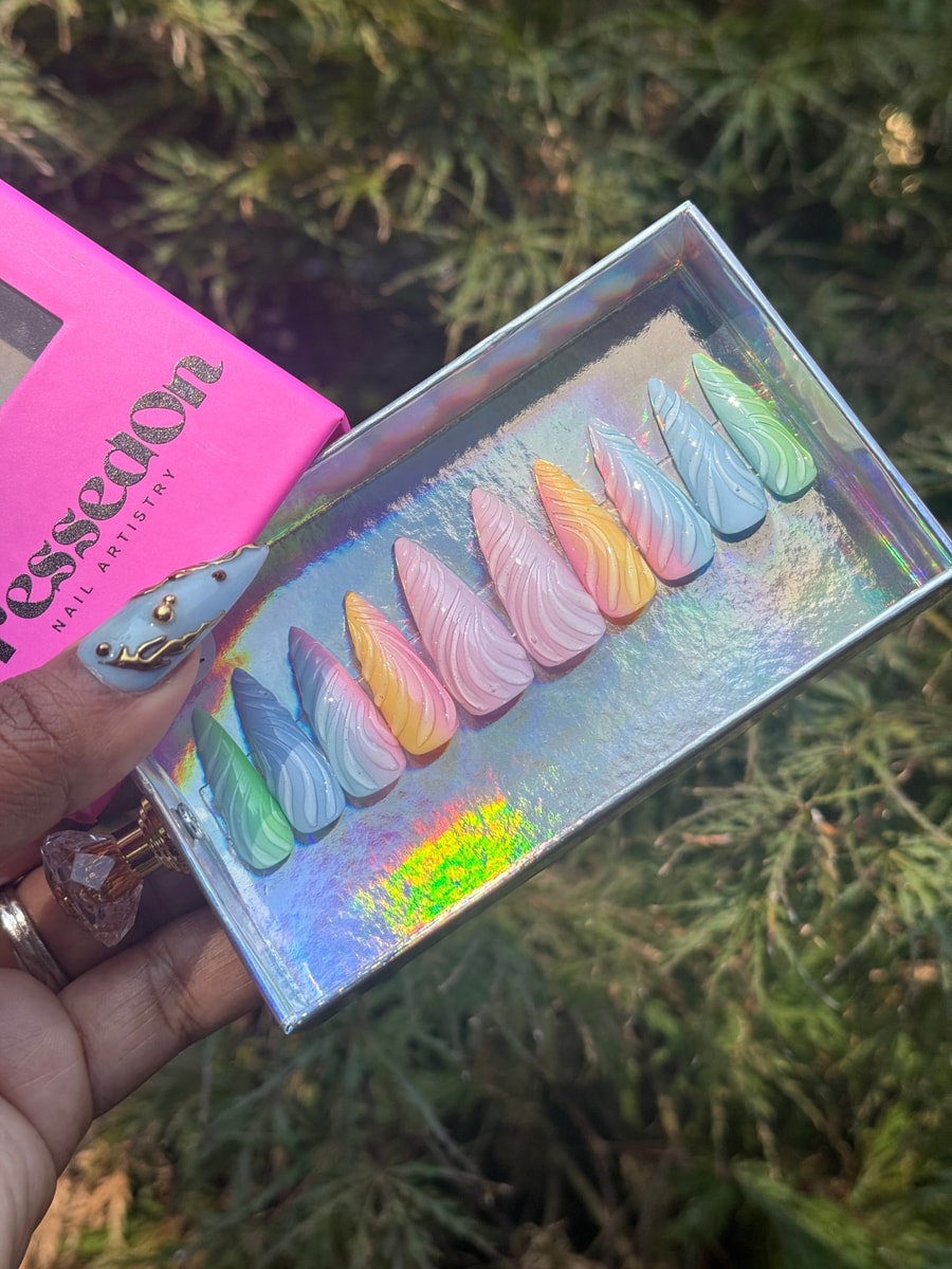 Multi-colored pastel press-on nails with a 3D swirl design. The nails vary in color, transitioning from green, blue, pink, and yellow.