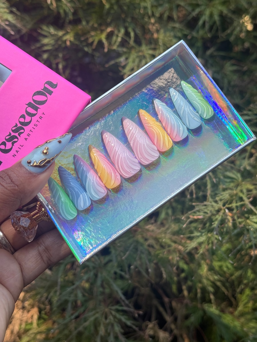 Multi-colored unicorn-inspired press-on nails with a pastel rainbow wave design. These are short stiletto shaped nails with a 3D effect.