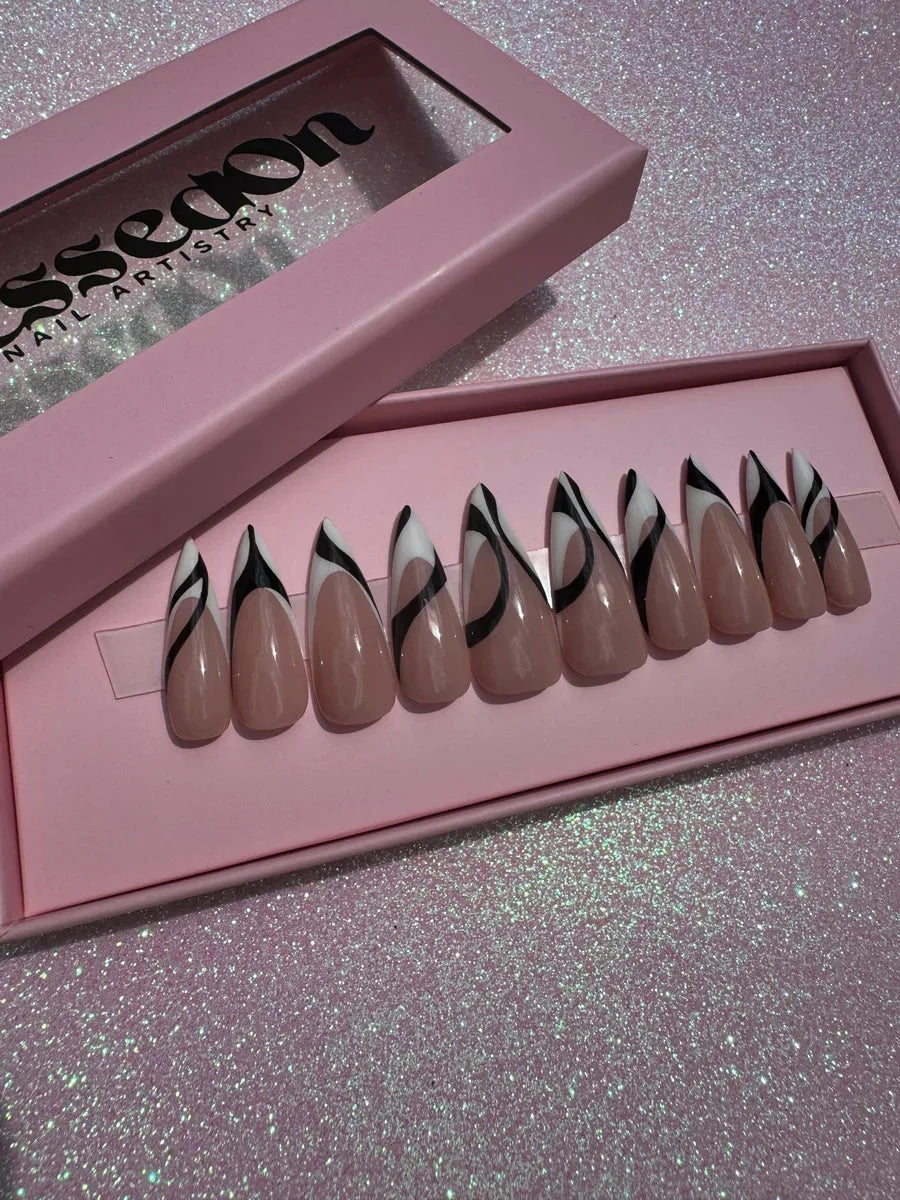 Set of nude almond press-on nails featuring a black and white swirl design on each nail. These medium-length nails offer a modern and stylish look.