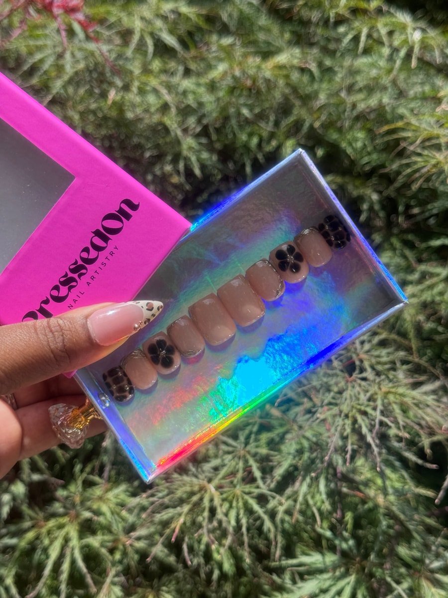 Super short nude press-on nails with black flower designs and animal print accent nails.