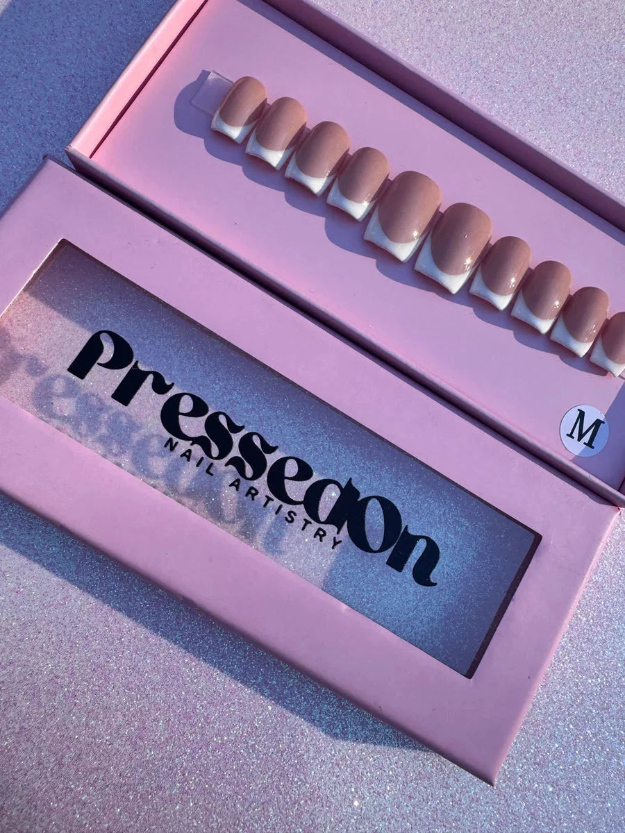 Super short press-on nails with a nude base and white tips in a French manicure style.