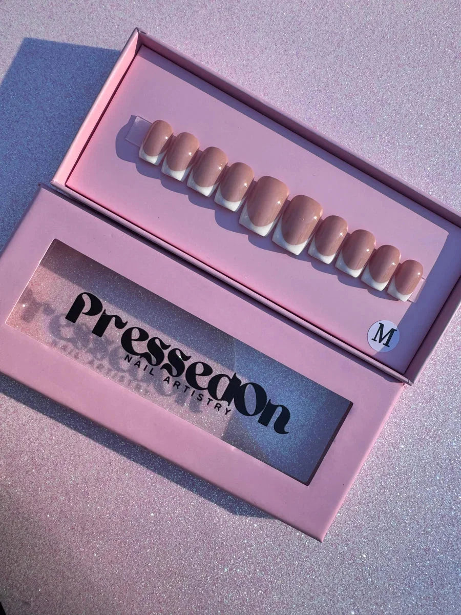 Short, square press-on nails with a nude base and white French tips. This is a full set of artificial nails for creating a classic manicure look.