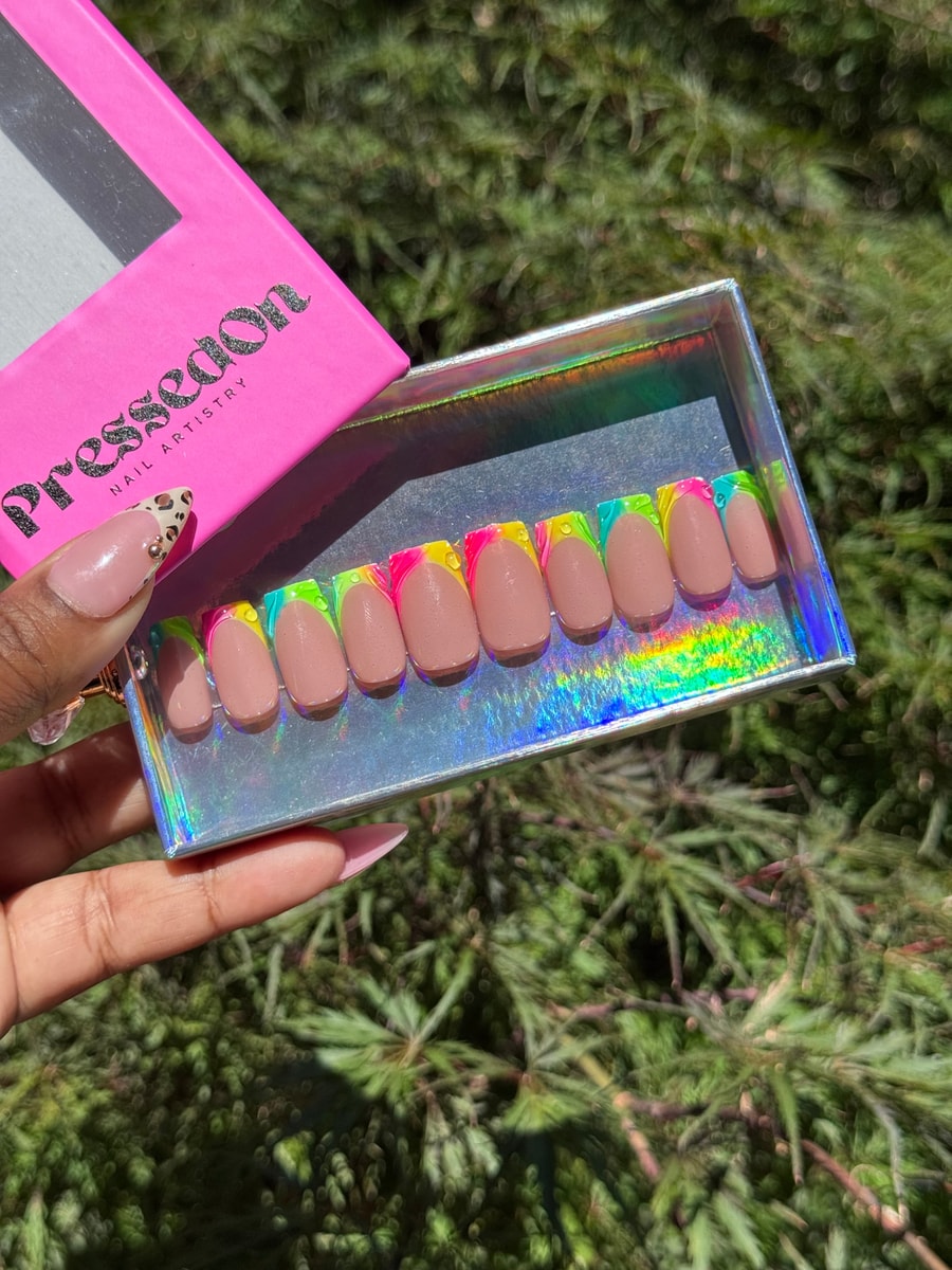 Set of super short nude press-on nails with a colorful French tip design. The tips are painted in neon pink, yellow, and green.