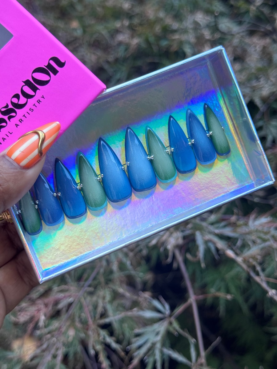 Ocean aura press-on nails with a blue and green gradient. Each stiletto-shaped nail has small silver bead accents near the base.