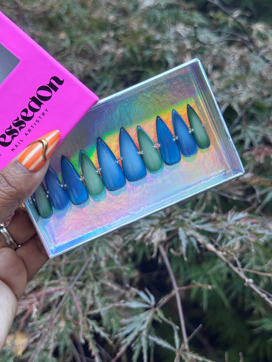 Set of blue and green medium stiletto press-on nails with a gradient ocean aura design, each accented with a small rhinestone.