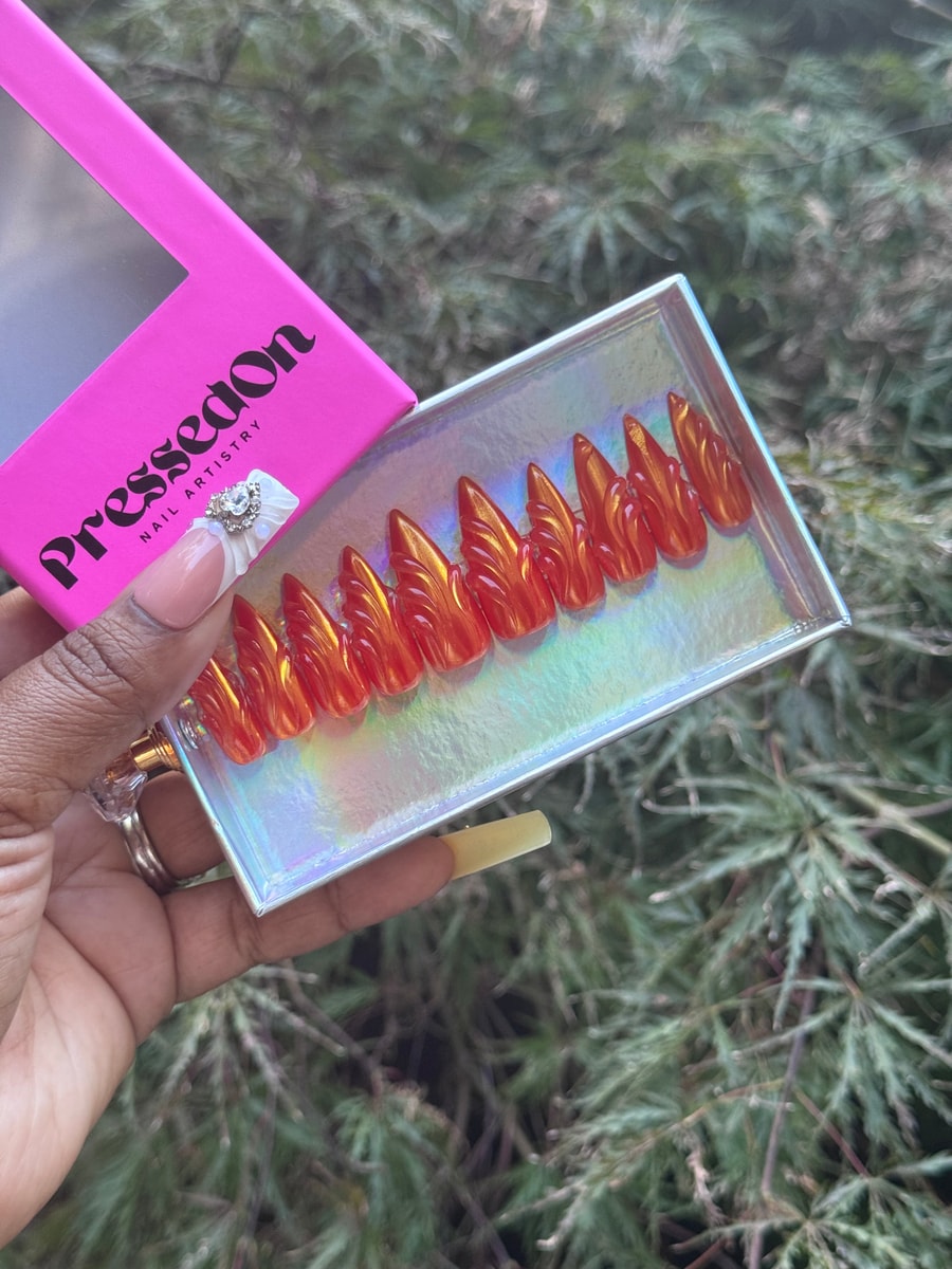 Orange medium press-on nails feature a textured, swirling design across each nail.