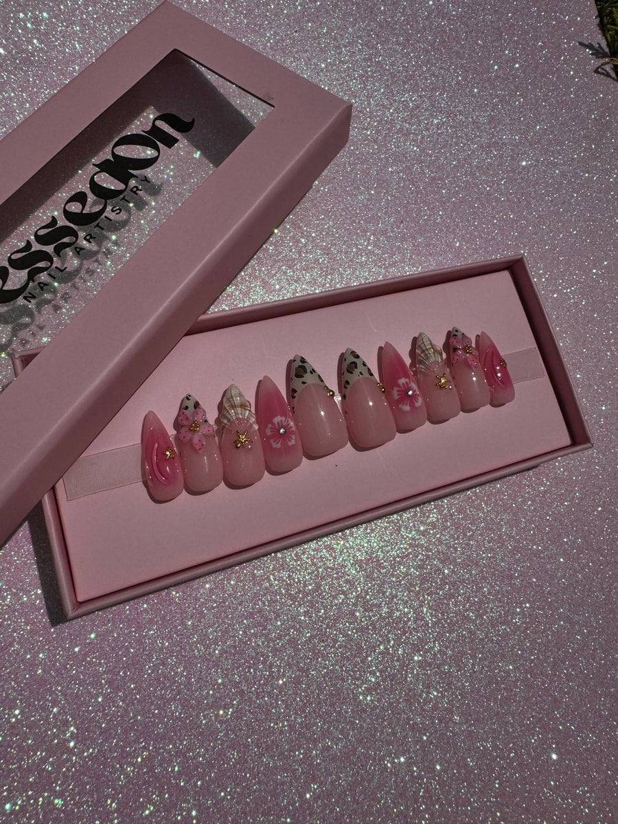 Medium pink press-on nails with cheetah print, floral accents, and gold embellishments.