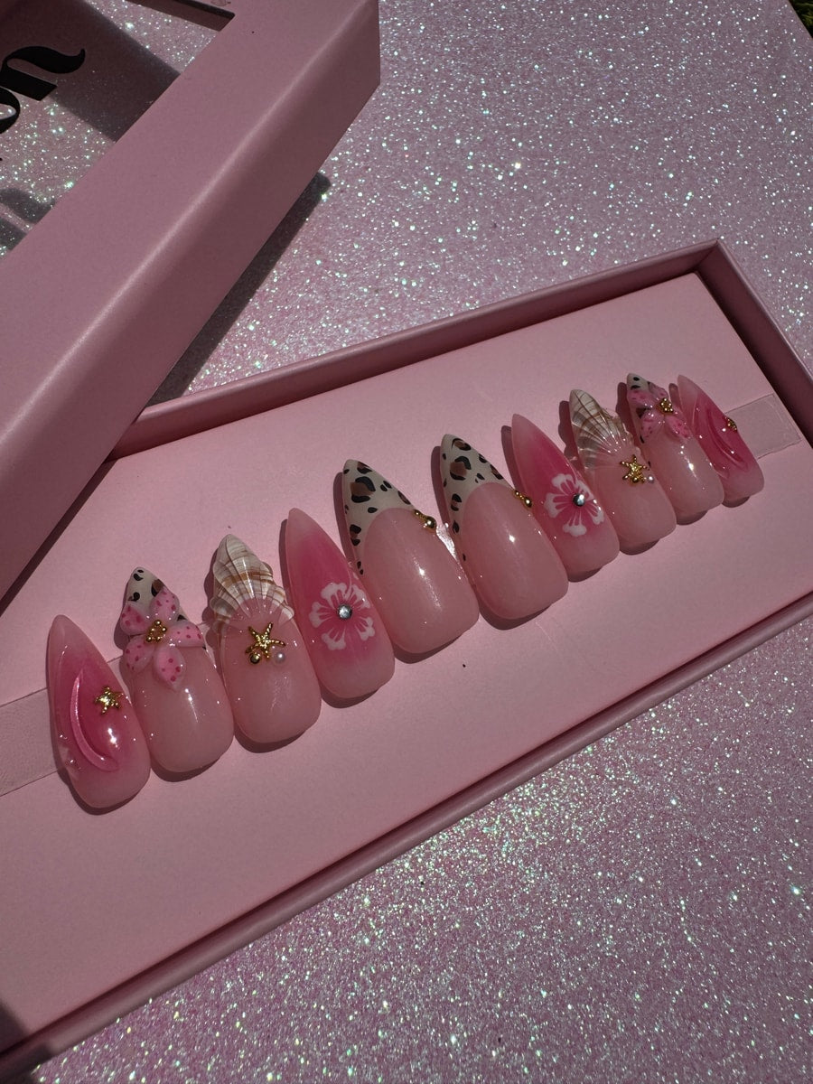 A set of medium-length pink press-on nails with cheetah print, floral designs, and rhinestone accents.