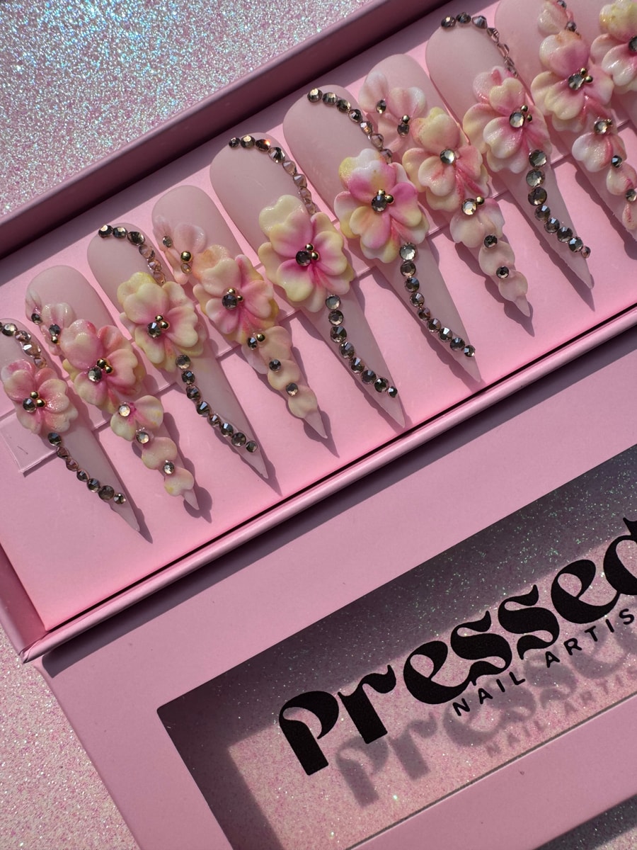 Extra long stiletto pink press-on nails decorated with delicate 3D flowers and sparkling rhinestones.