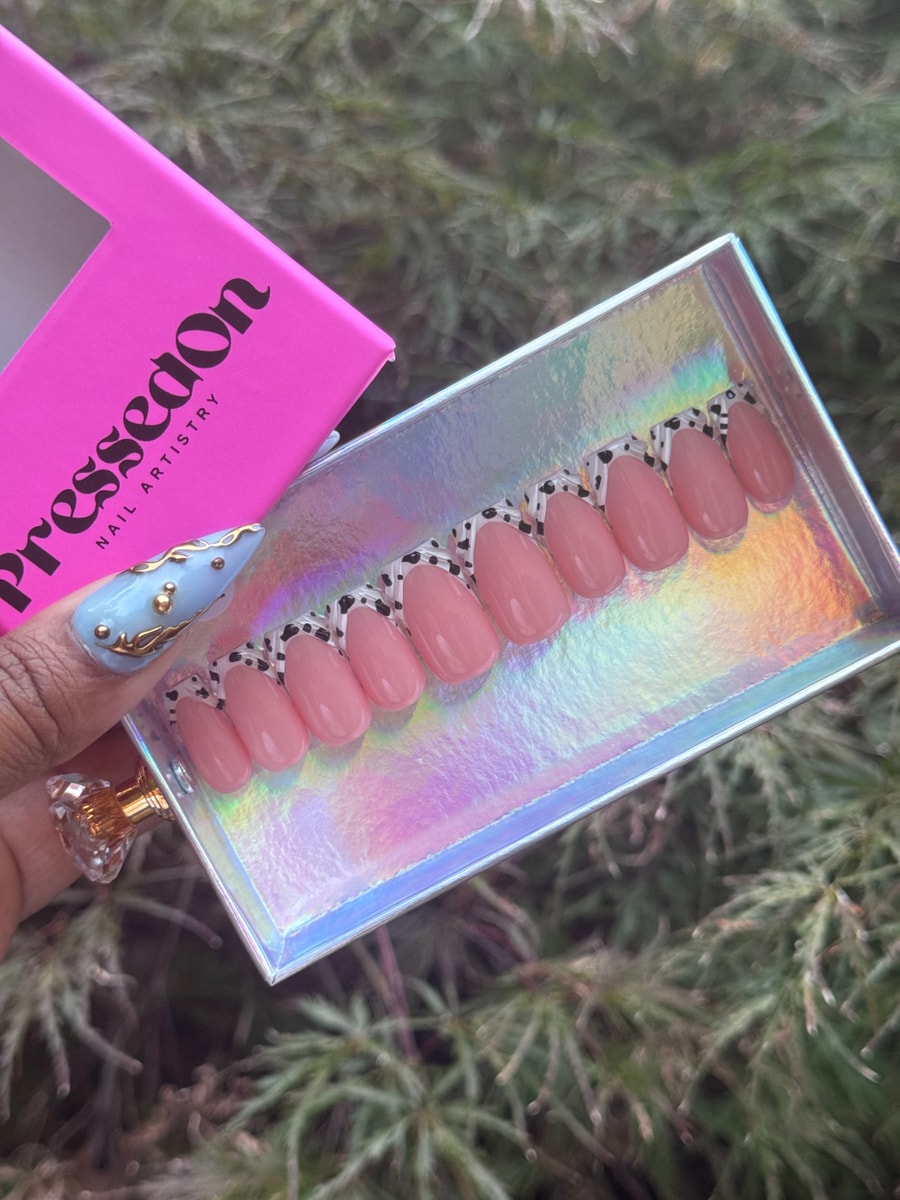 Short, almond-shaped pink press-on nails feature a cow print French tip design.