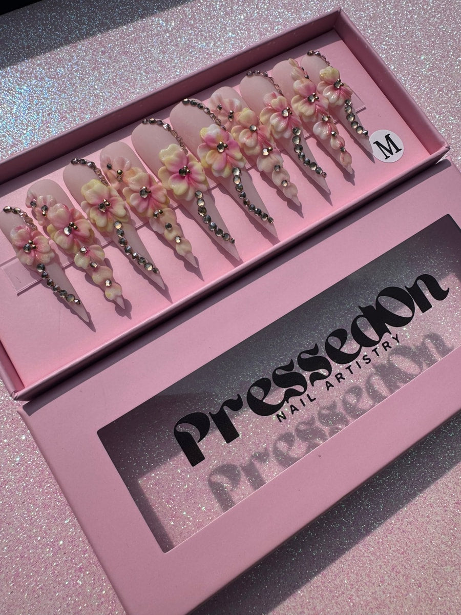 Xtra long stiletto press-on nails are light pink with 3D flower embellishments and silver rhinestone accents.