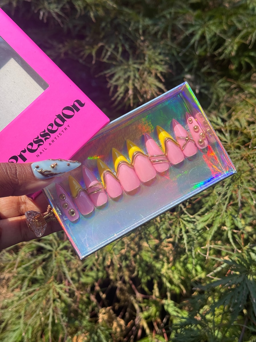 Pink and yellow stiletto-shaped press-on nails featuring a gold wire design and gold bead accents.