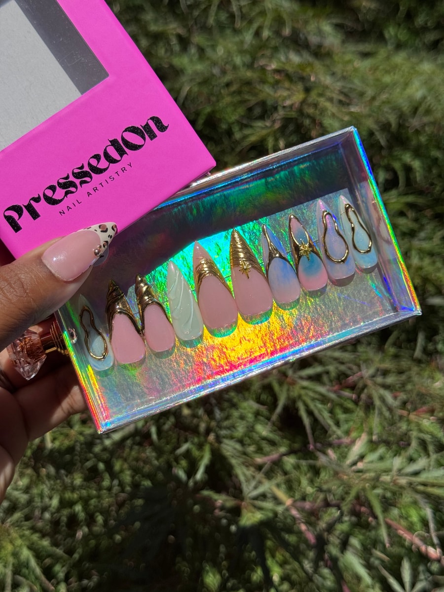 Set of medium-length princess-style press-on nails featuring chrome gold accents and abstract designs on a light pink and blue base.