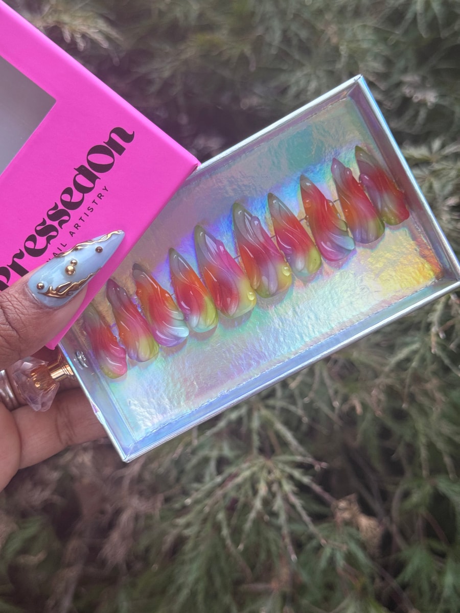 Medium stiletto press-on nails with a jelly finish show a rainbow gradient of red, orange, yellow, green, and purple.